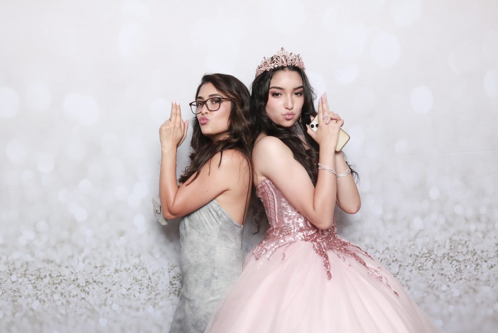 Sofia's Quinceanera with friend posing in matching beige backdrop for her photo booth rental in Anaheim, CA