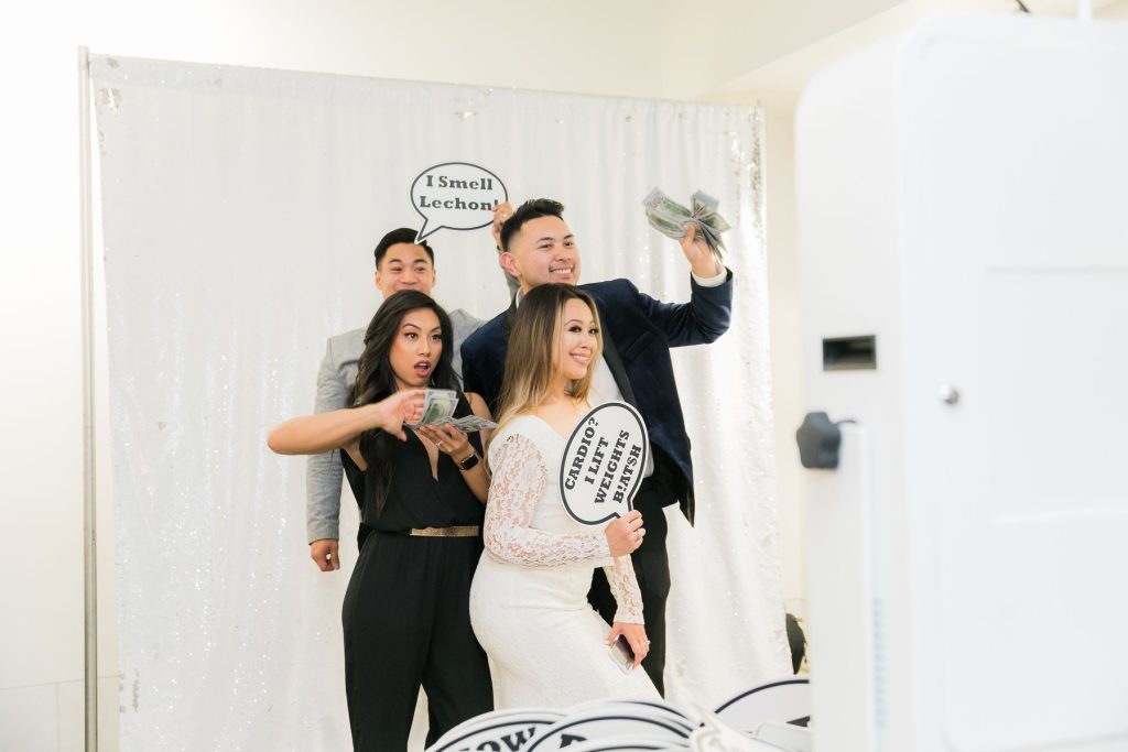 Newlyweds and guests taking a selfie with custom hand held sign props at Karla and Paul’s final fiesta in a Step Inside My Booth open air photo booth in Chino Hills, California